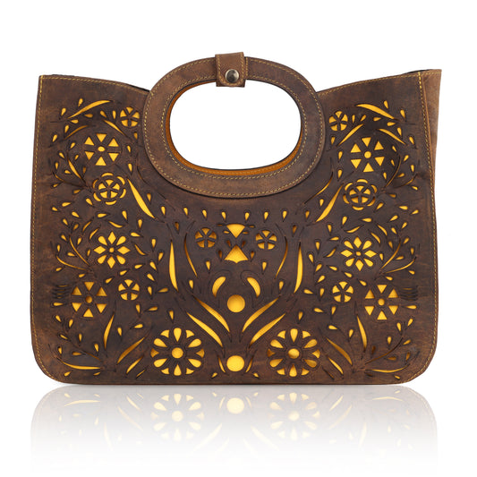 This unique tote bag features an intricate laser-cut floral pattern on rich brown leather, with a golden inner lining that shines through the cutwork for a striking effect
