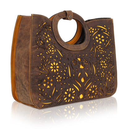 This unique tote bag features an intricate laser-cut floral pattern on rich brown leather, with a golden inner lining that shines through the cutwork for a striking effect